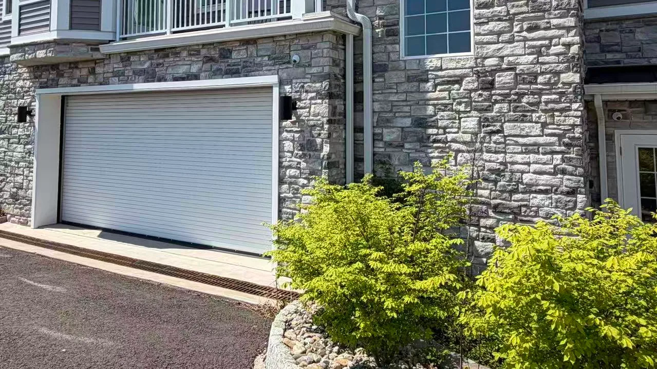 Private garage entrance below stone-clad facade and balconies